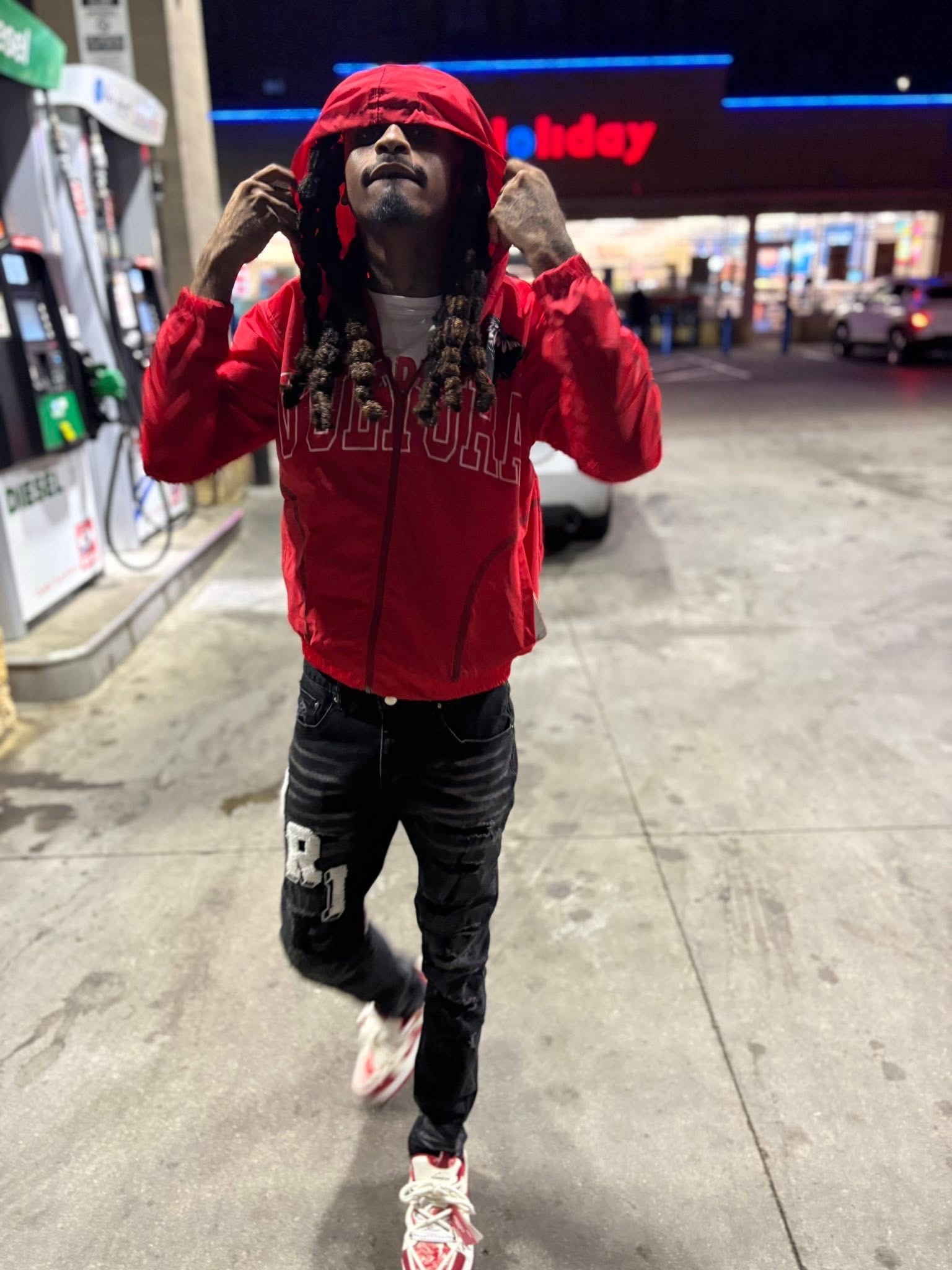 KT Mello wearing a red jacket at a gas station